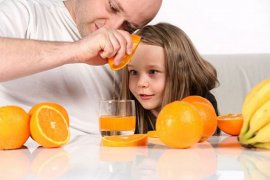Свежевыжатый сок из апельсина готовит ребенок с папой